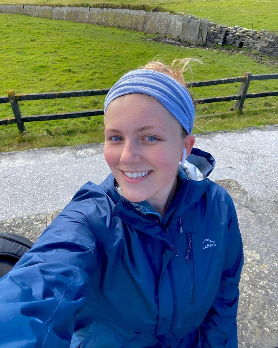 Student takes a selfie in front of a green pasture in Ireland.