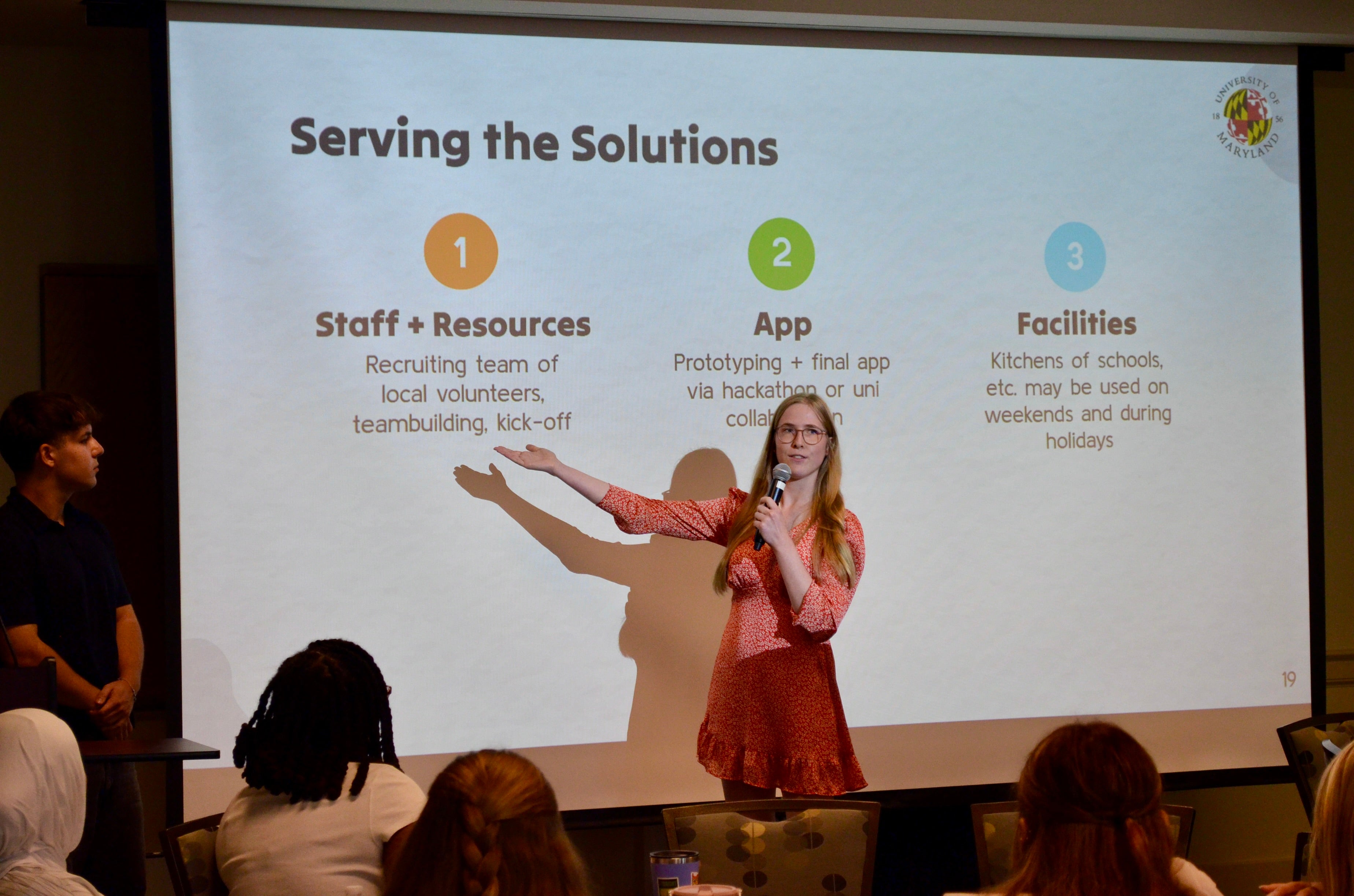 Young woman delivers a presentation, pointing to a slide