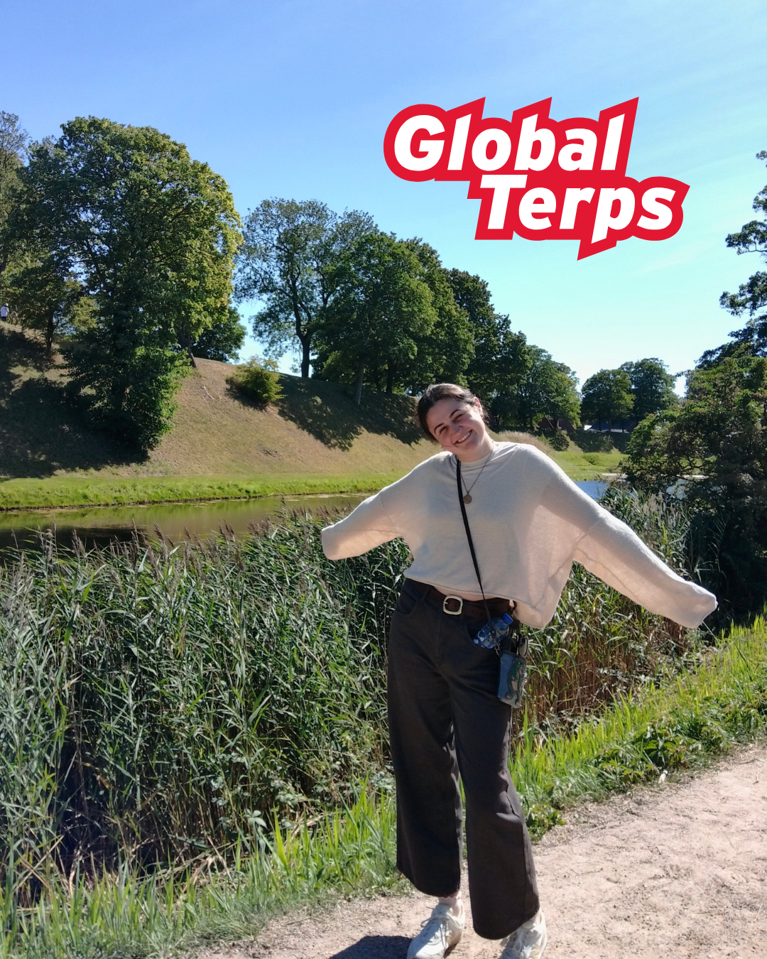 Young woman stands on walking trail in front of a body of water