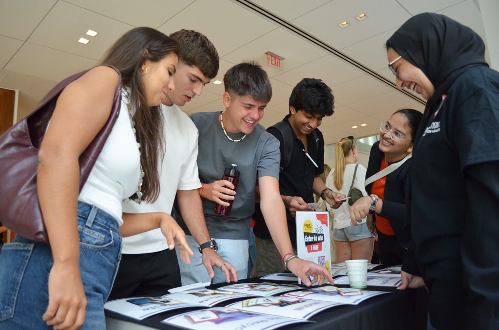 Students gather around a table to play a game where cards are matched to flyers
