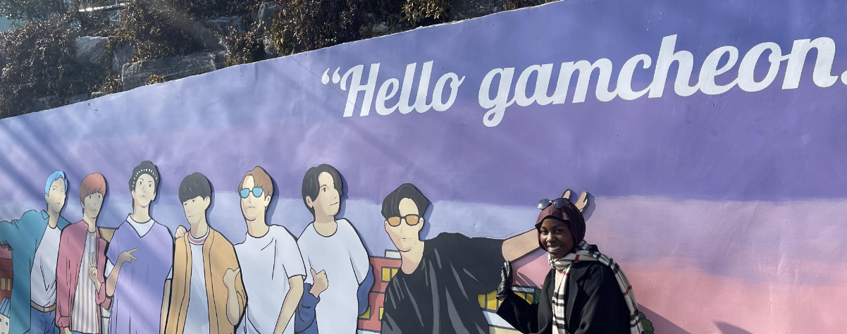 N'Deye Diop poses in front of a mural in Korea.