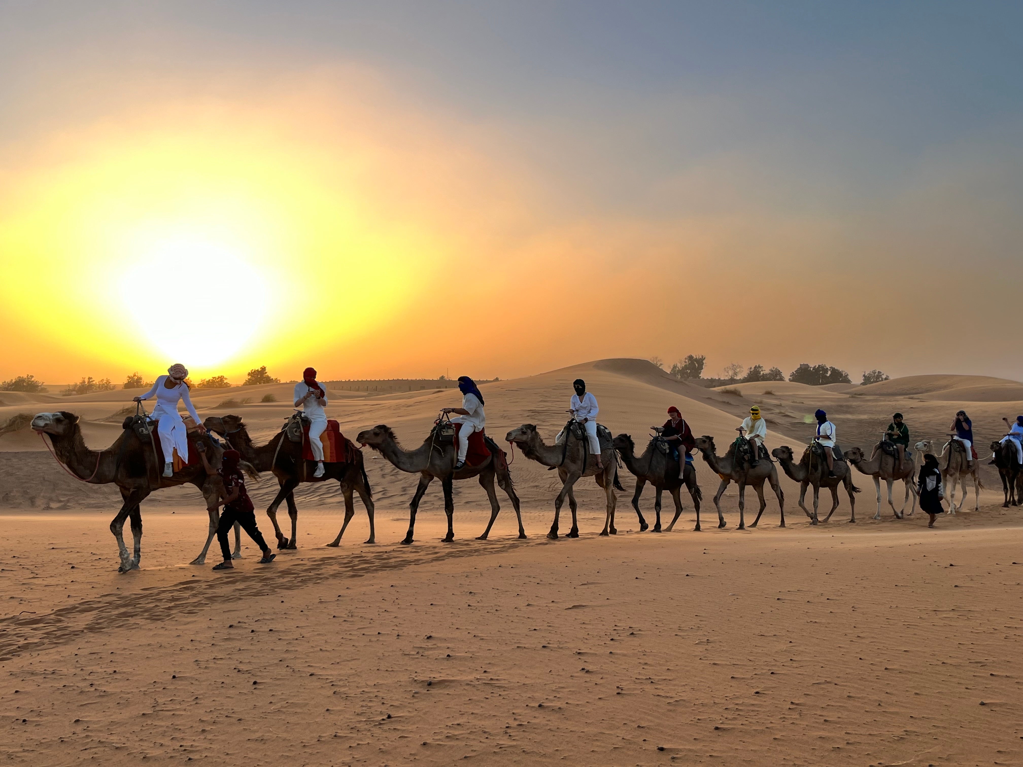 Students ride camels and sunset across the dessert. 
