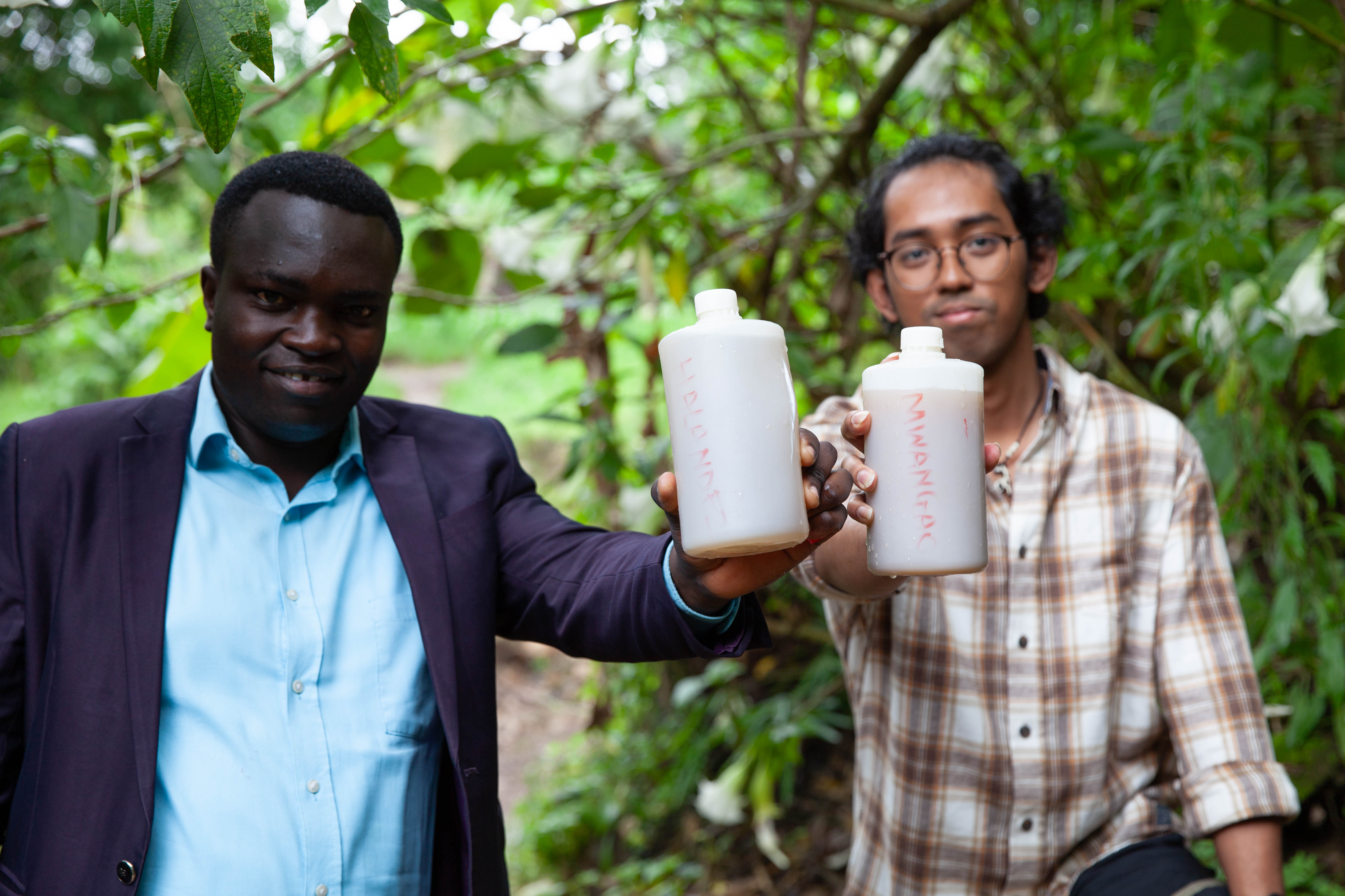 Andhikaputra (r) and MUST staff Abolom Komanya hold marked water samples collected from two creeks outside of Mbeya, Tanzania.