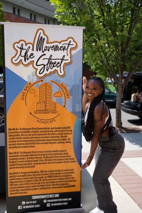 Woman standing next to a pull-up banner with information about The Movement Street organization