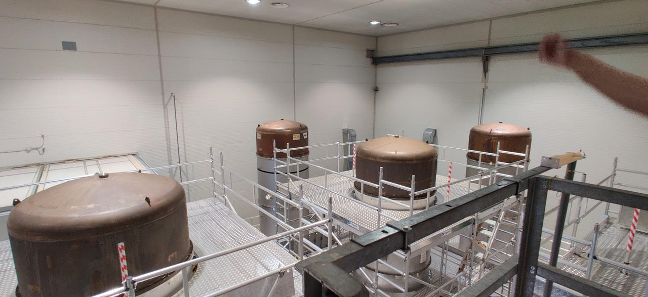 Four tall cylinders with scaffolding around them, vibration isolation systems inside the Gravitational Wave Observatory, Pisa, Italy.