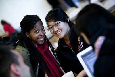 Two students smile by a laptop.