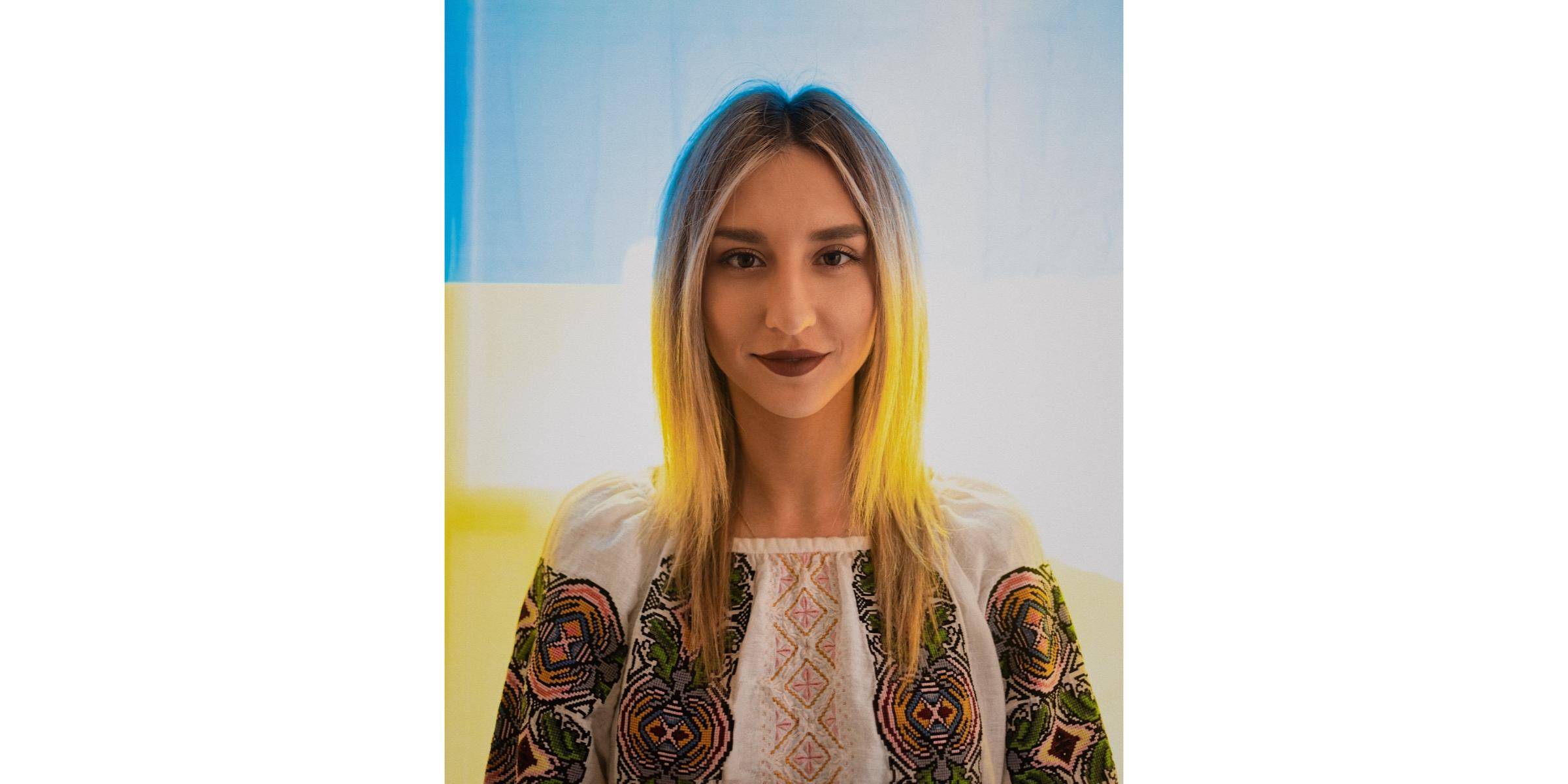 Tetiana Tytko poses for a headshot in front of the Ukrainian flag.