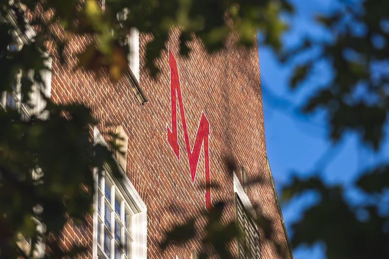 Maryland "M" image painted on the brick exterior of a building against a blue sky.