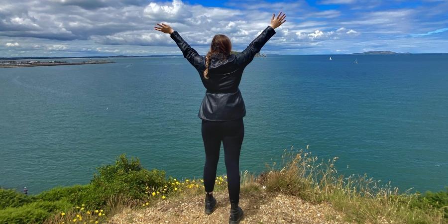 Audrey Bartholomew '23 stands on a cliffside overlooking the ocean in Howth, Ireland.