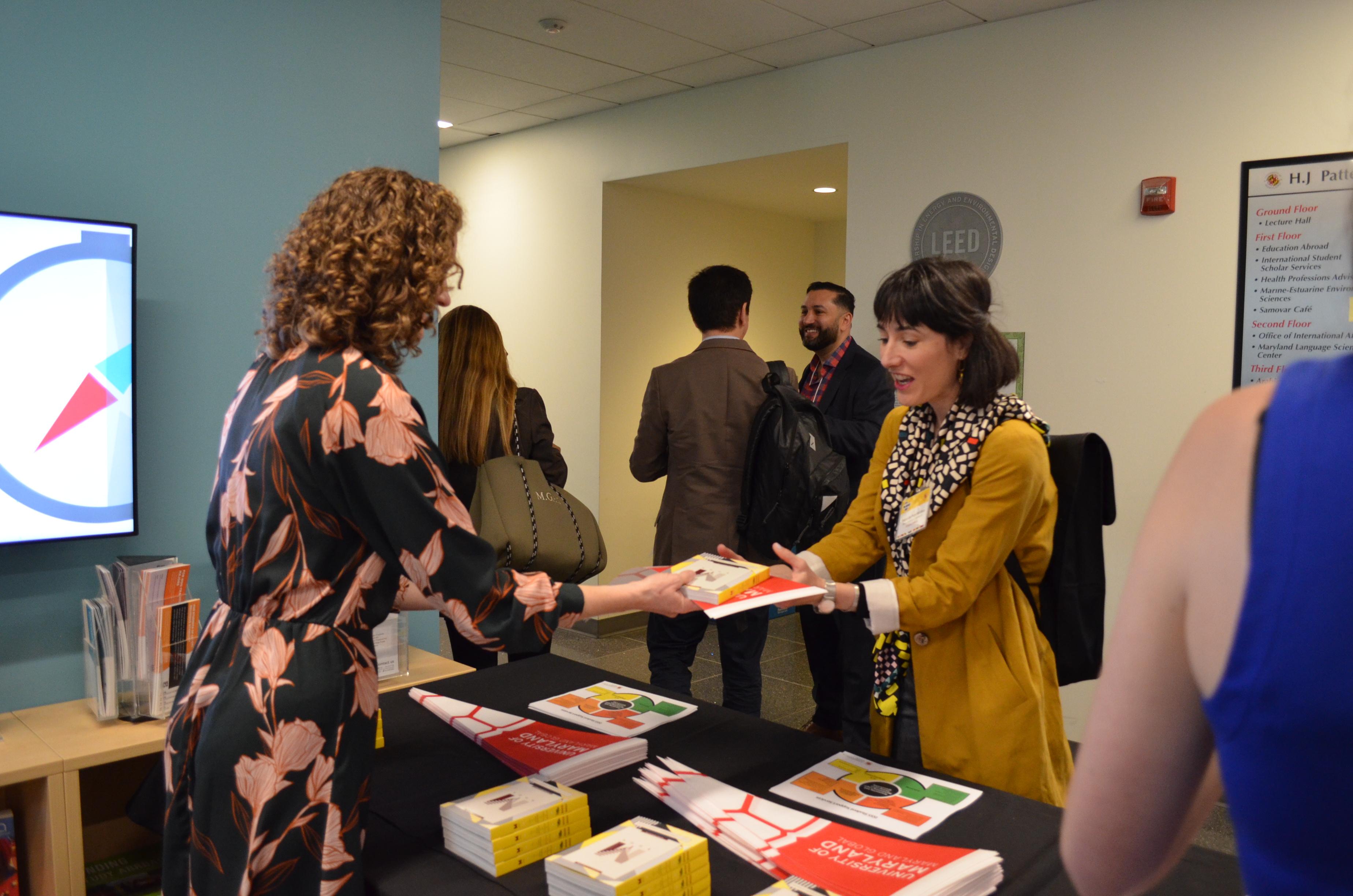 Two faculty members convene over a table. 