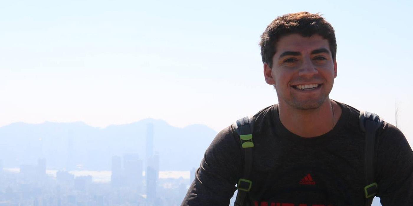 Alexander sitting in front of the Hong Kong skyline