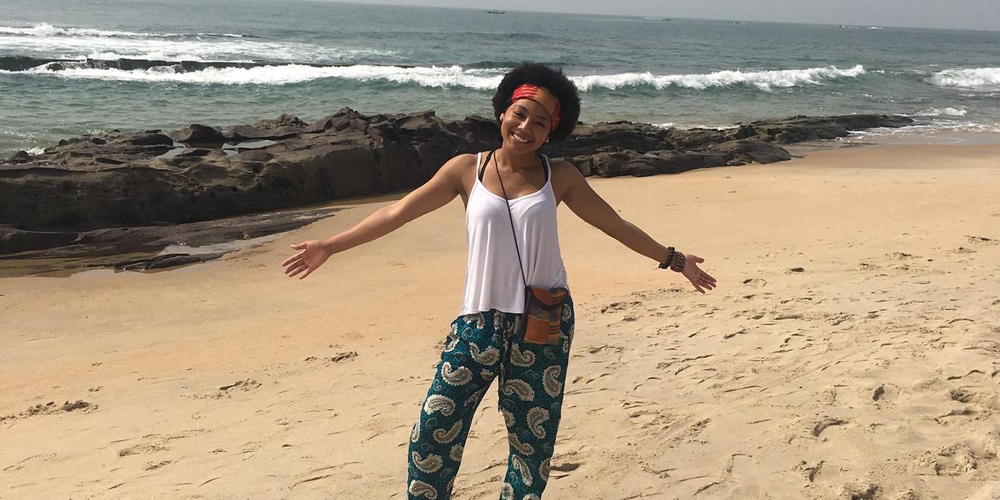 Alexis standing in front of the waves on the beach with her arms open