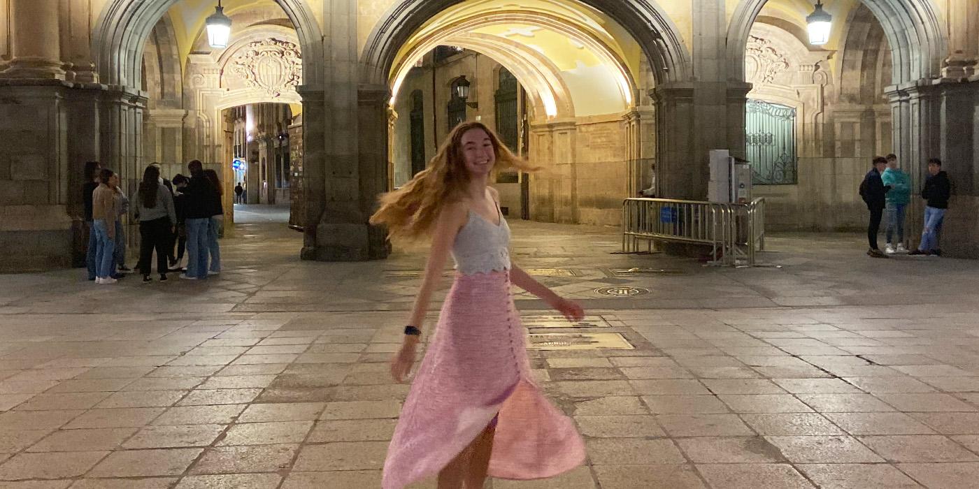 Amanda Radko twirls around while wearing a pink and white dress inside a Spanish cathedral