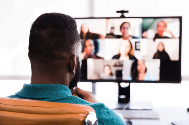 Back of a man's head as he sits at computer on a video conference