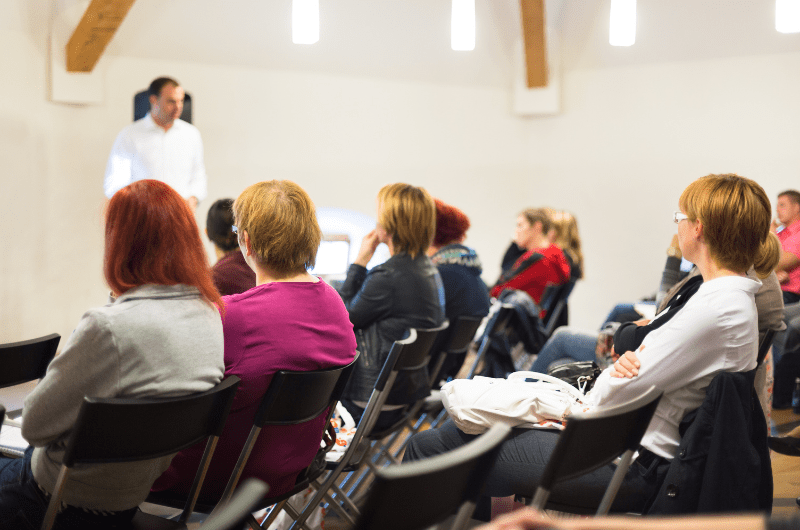 People sitting in rows of chairs facing a speaker