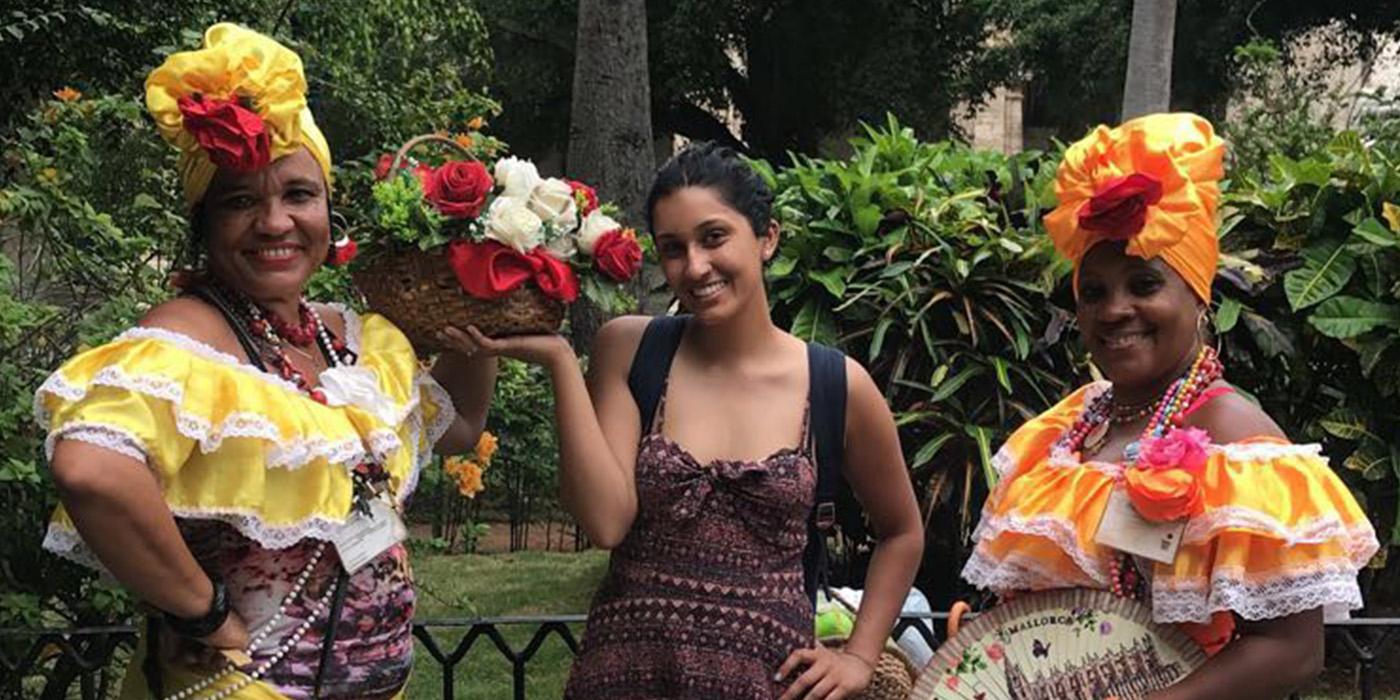 Fareeha standing between two women in traditional Cuban dress