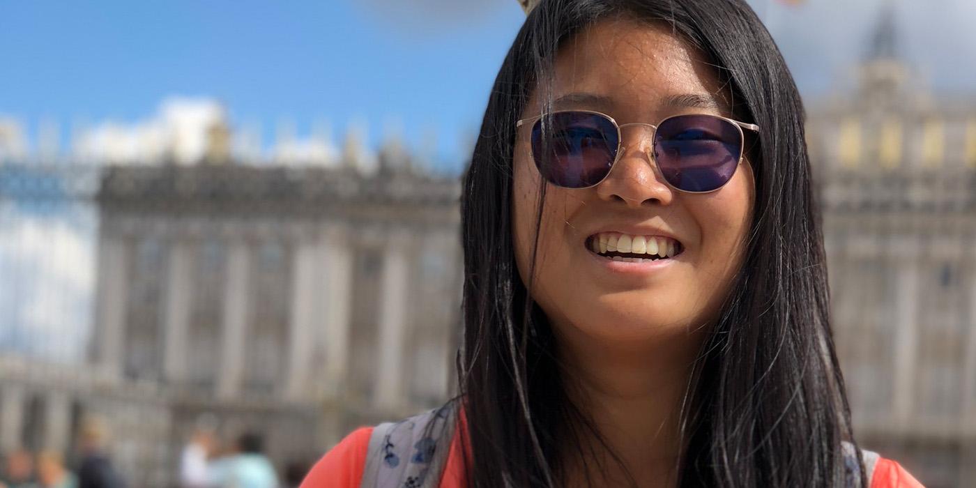 Joanne smiling with sunglasses on, in front of a large building with columns