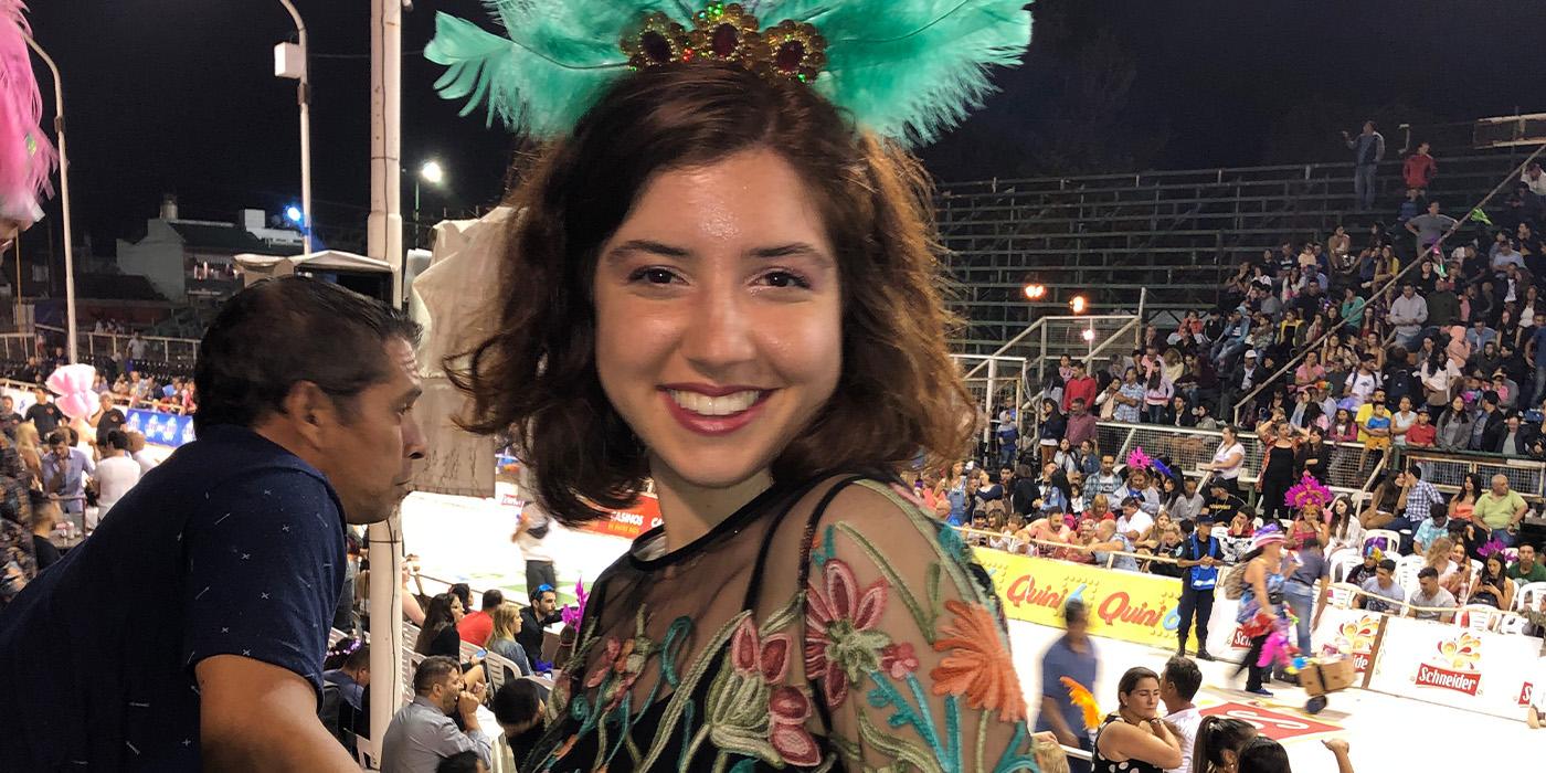 Meredith McVadon wears a blue feathered hat in a crowd during an outdoor event