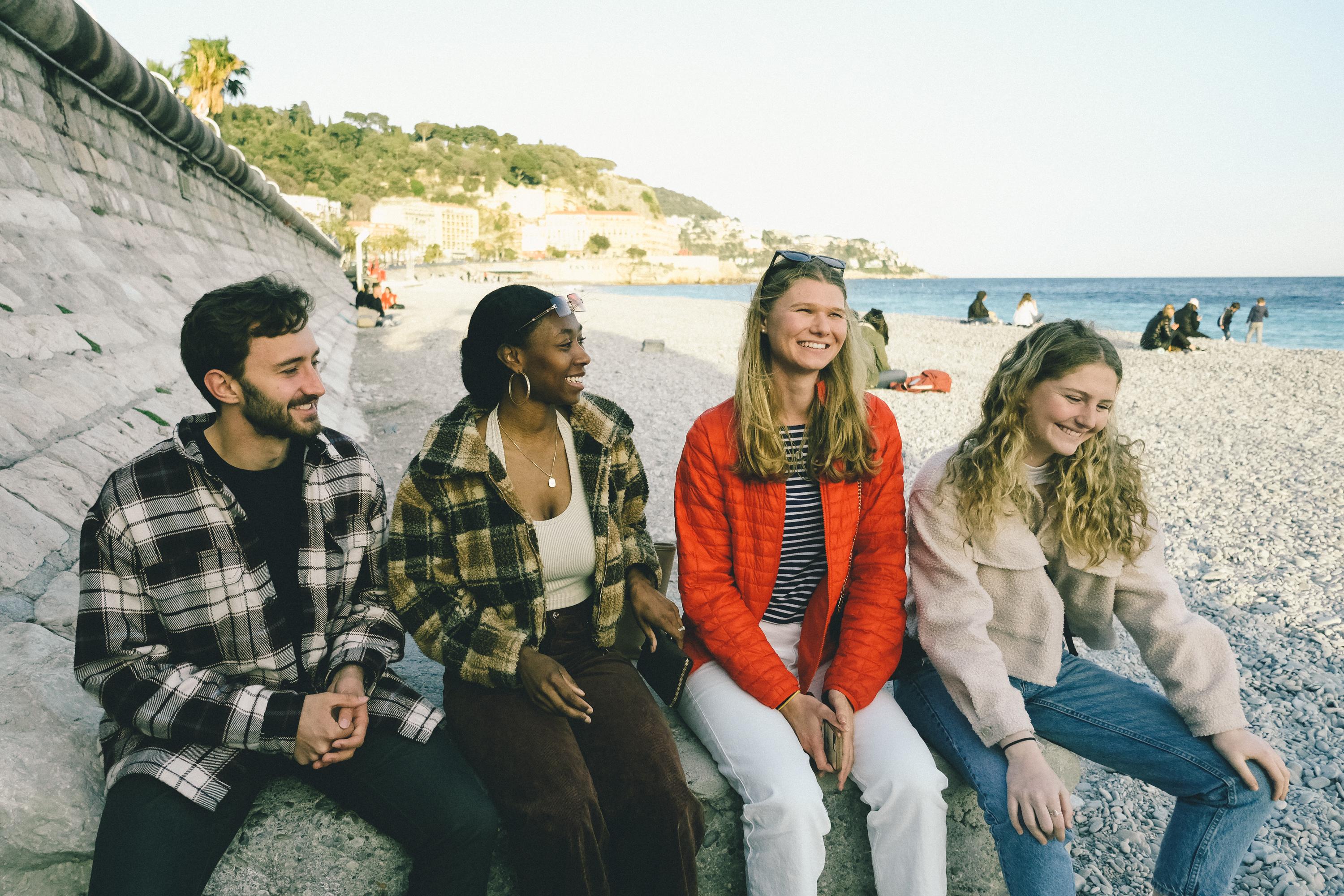 A group of four students sit on the beach in Nice, France.
