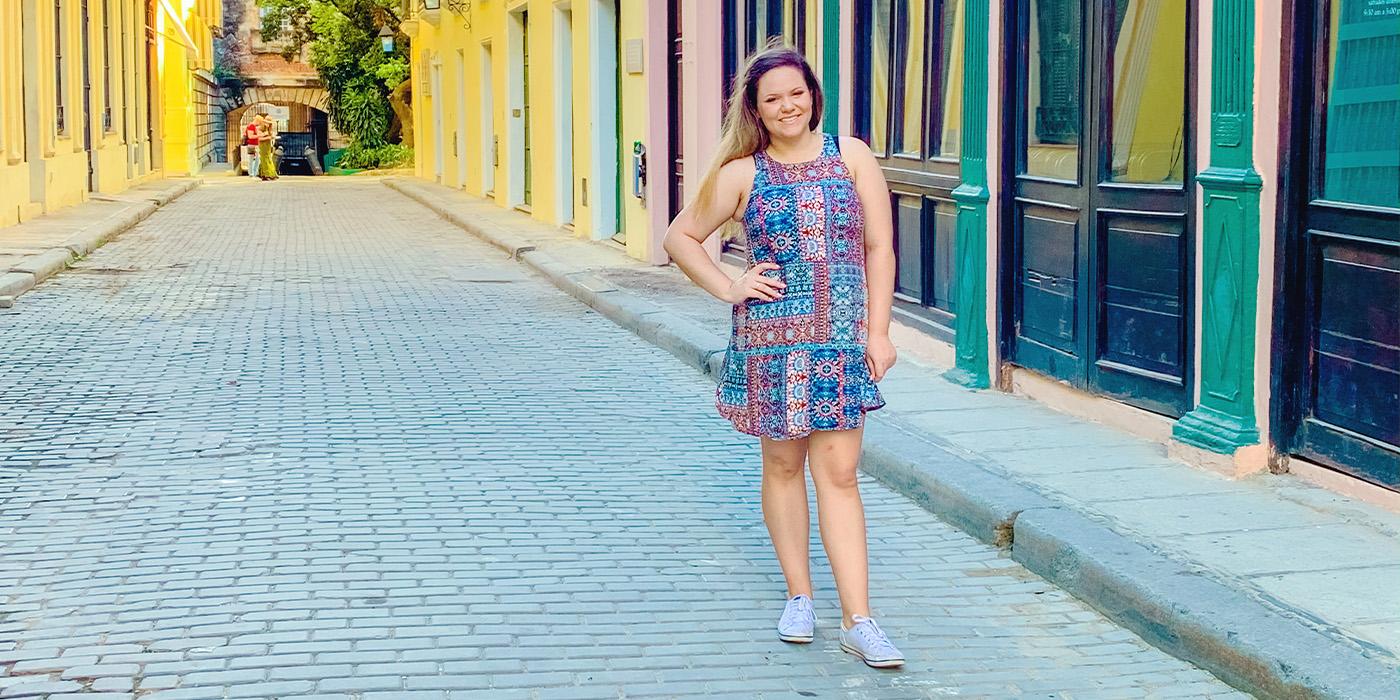 Nikita Mutter poses in a patterned dress on a colorful street in Cuba
