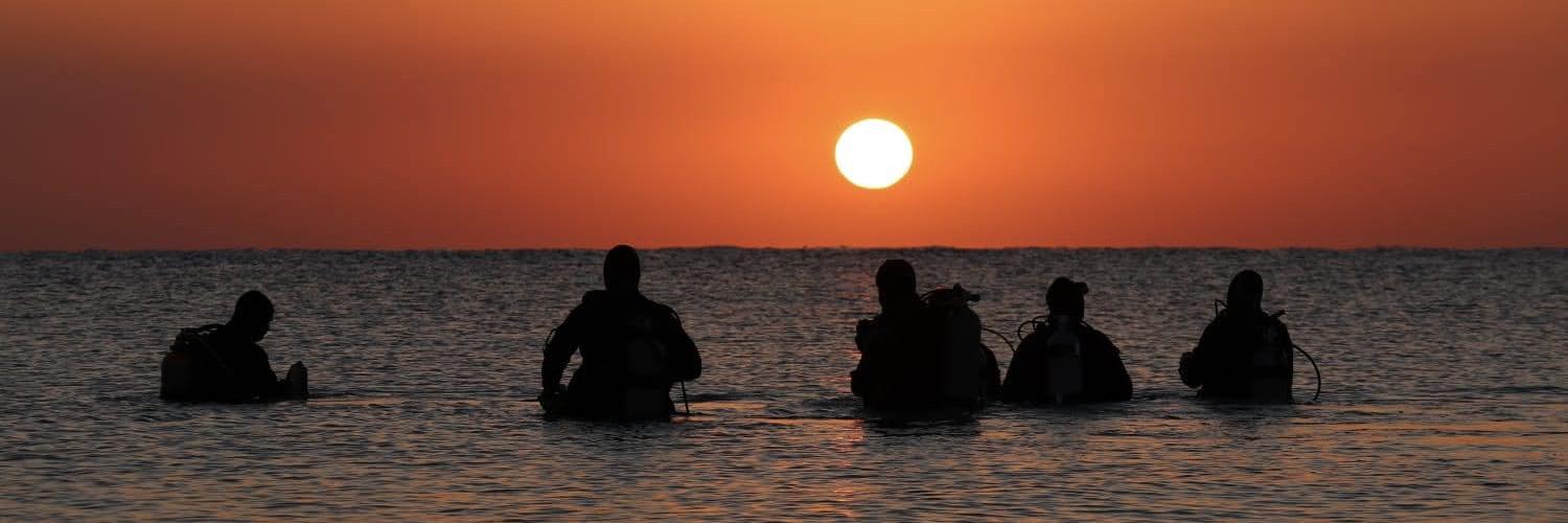 Divers getting read for a night dive in the Red Sea at sunset in Marsa Shagra, Egypt.