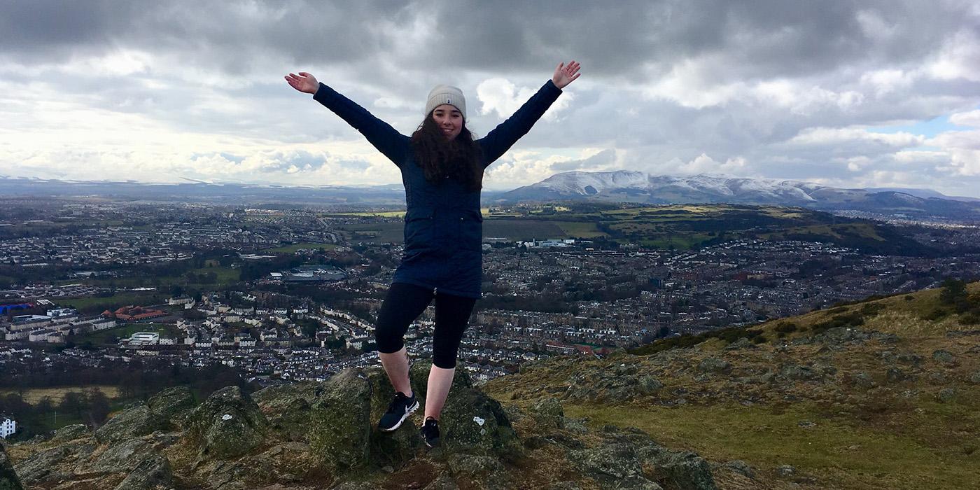 Shiri standing with her arms raised at Arthur’s Seat (near Holyrood Park), Edinburgh, Scotland