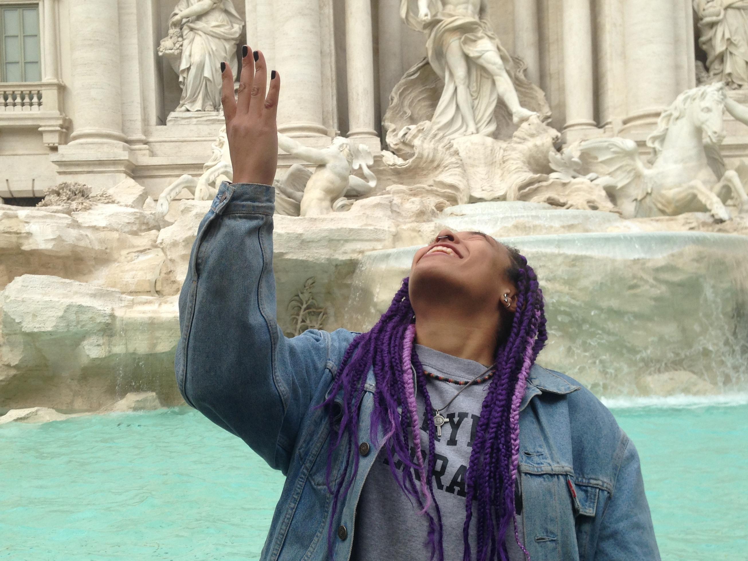 Student throws a coin into the Trevi fountain.