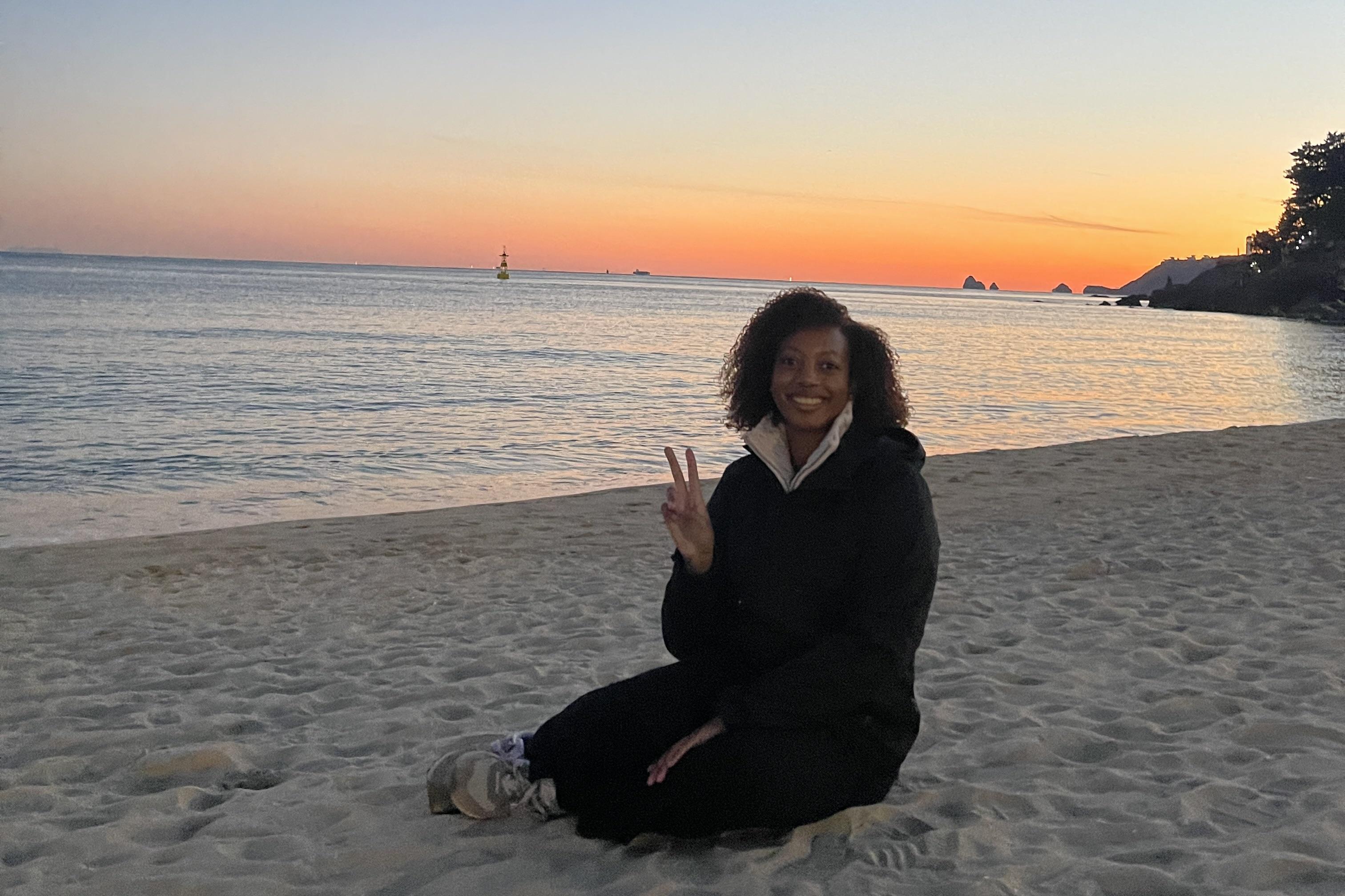 Alyssa Taylor sits on a beach a sunset
