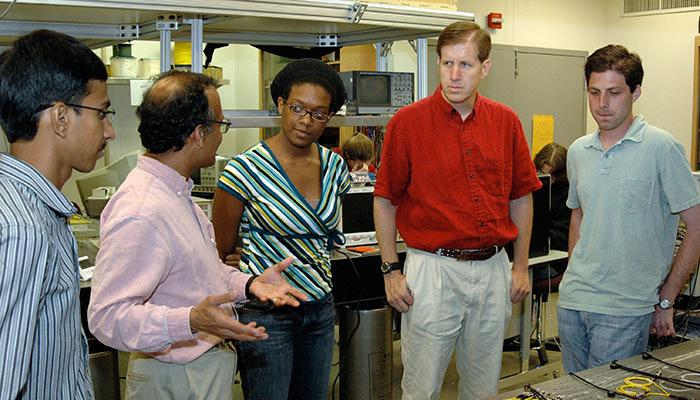 UMD staff pose with students in a lab.