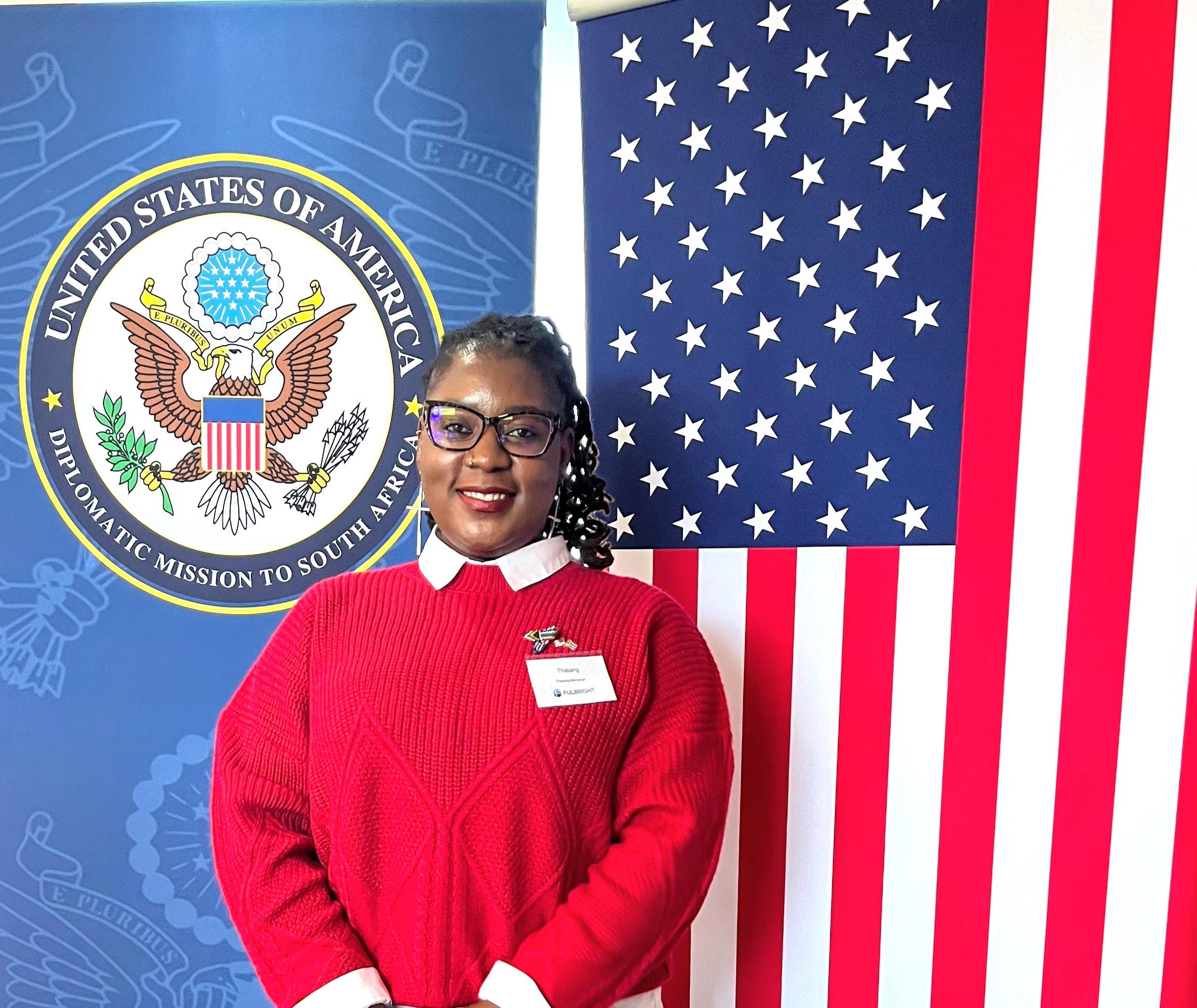 Visiting Fulbright scholar Thabang Msimango poses in front of the American flag.