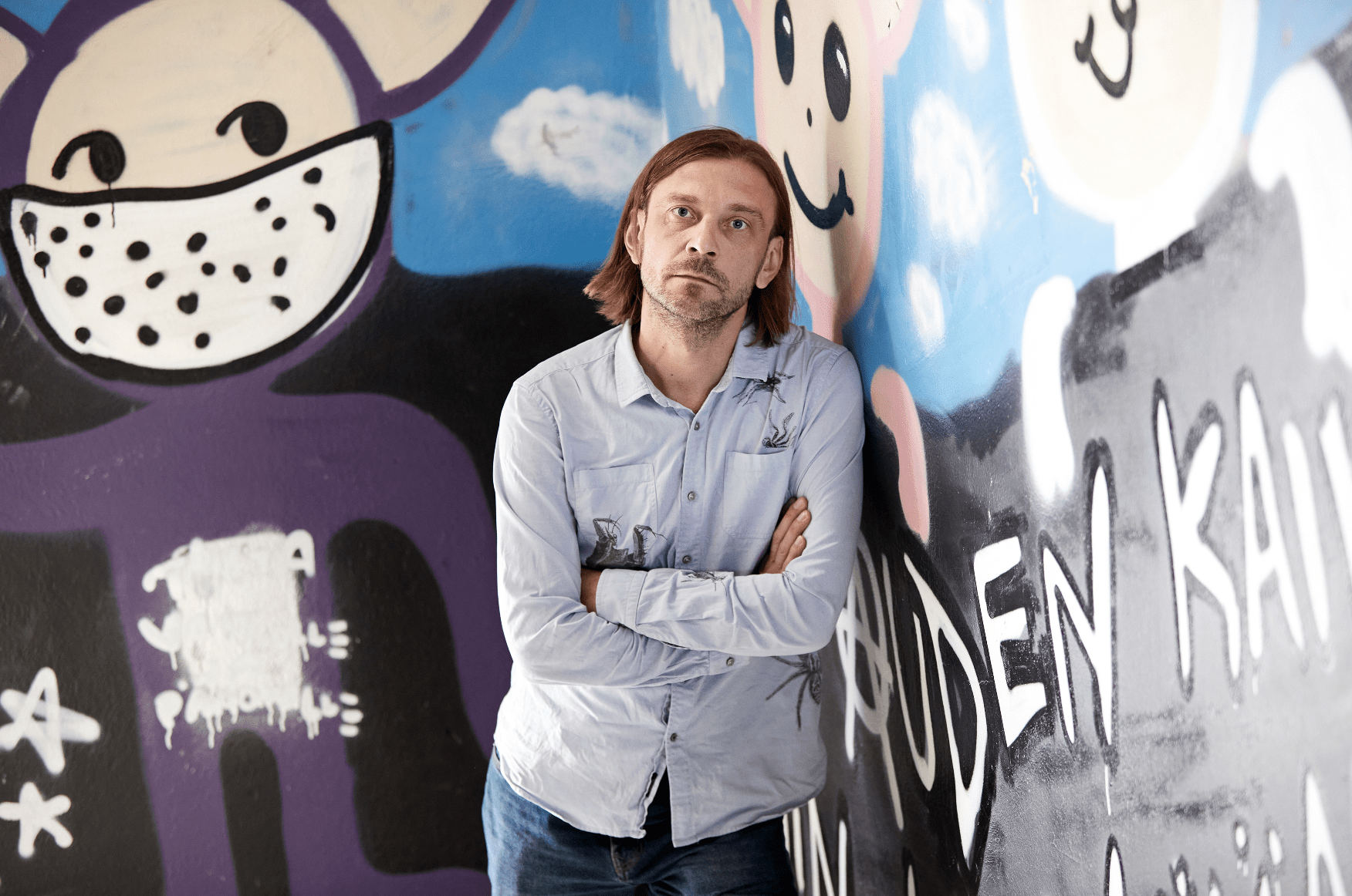 Russian playwright Mikhail Durenkov poses in front of a mural.