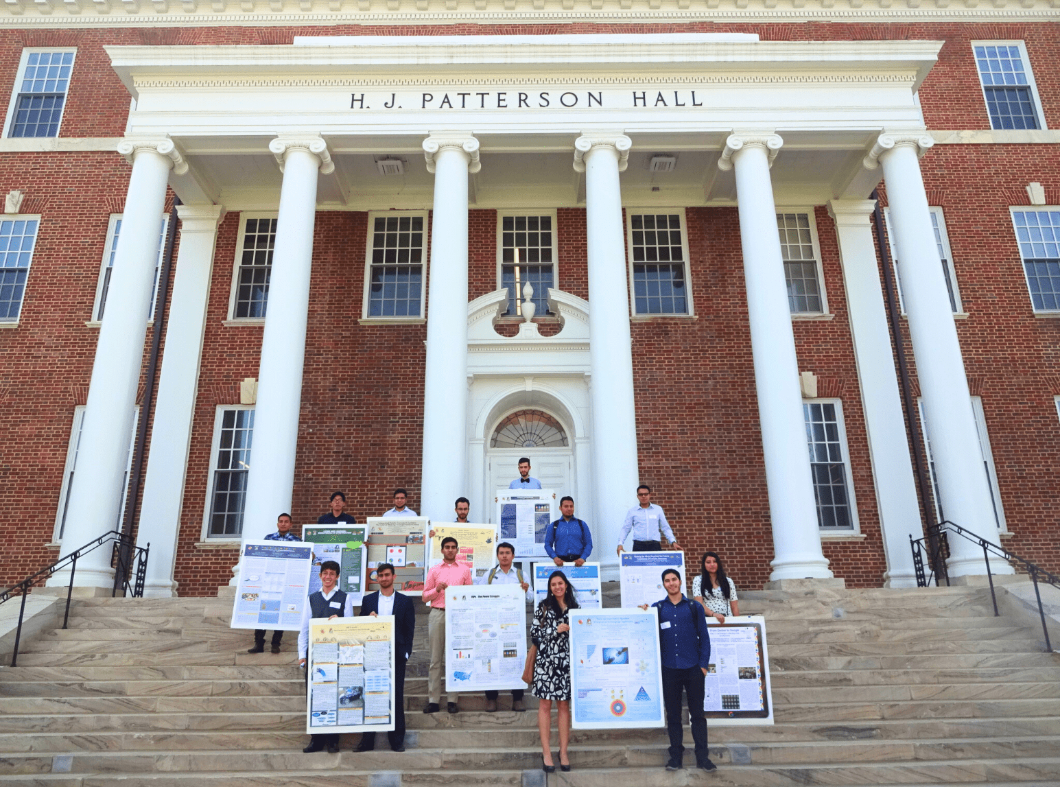 Students holding Global Classrooms End of Year Showcase posters on the steps of HJ Patterson