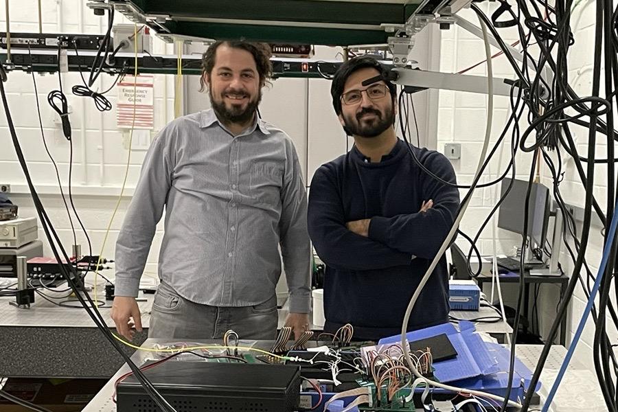 Chris Vagionas stands in a lab with colleague