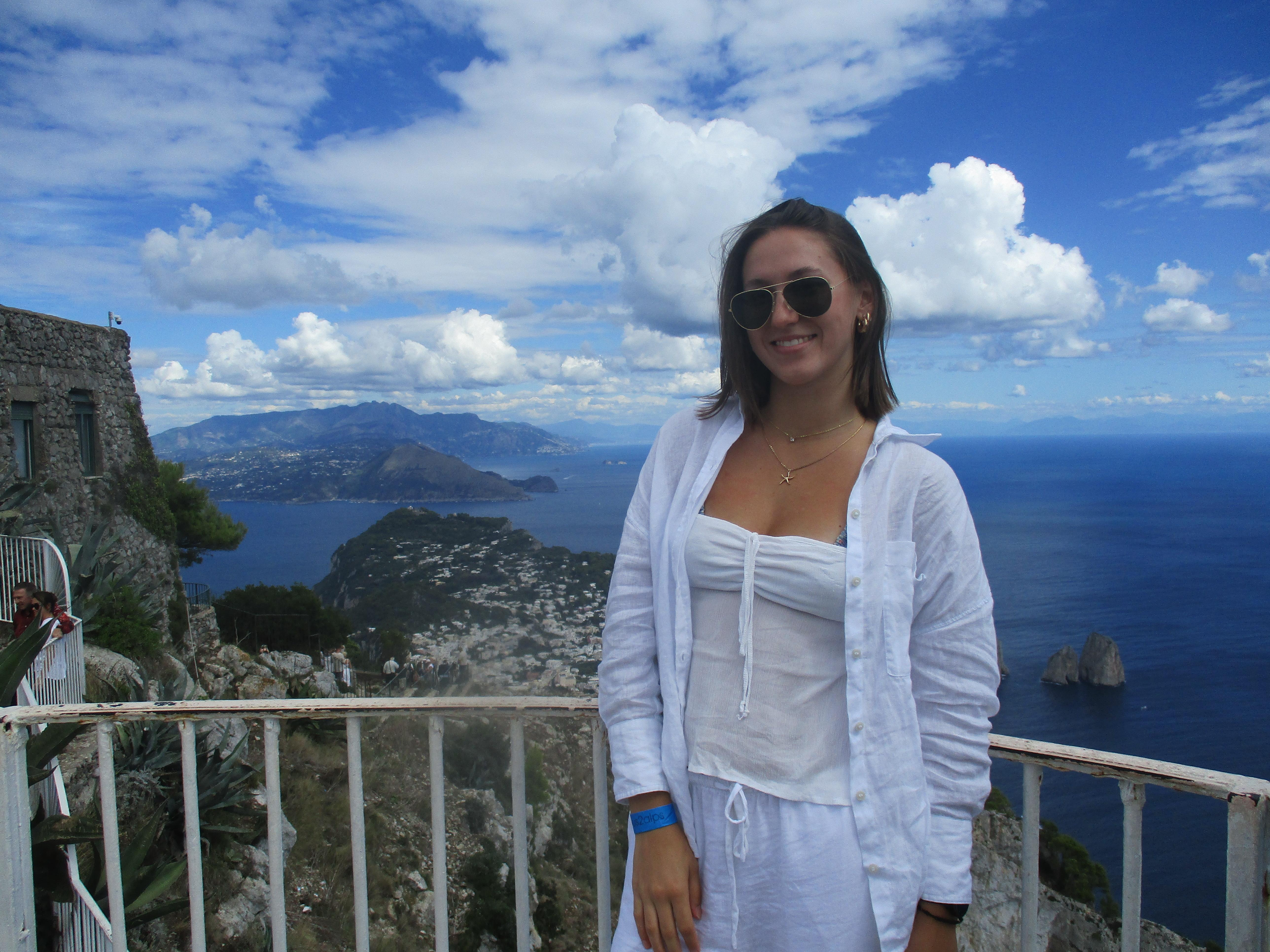 Maeve Campbell stands on a balcony overlooking the ocean. 