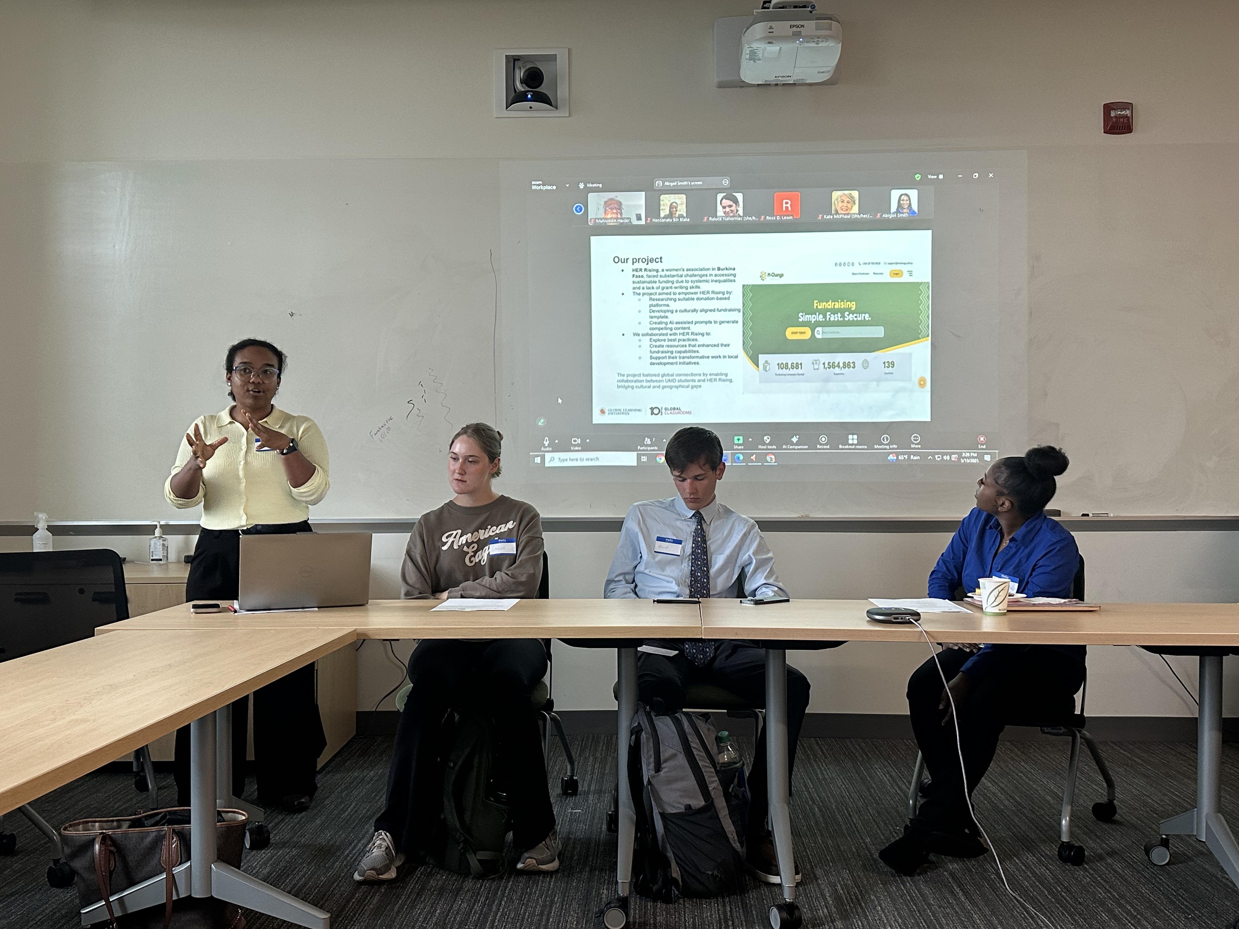 Student gives presentation to classroom. Three other students sit and wait to give their presentation.