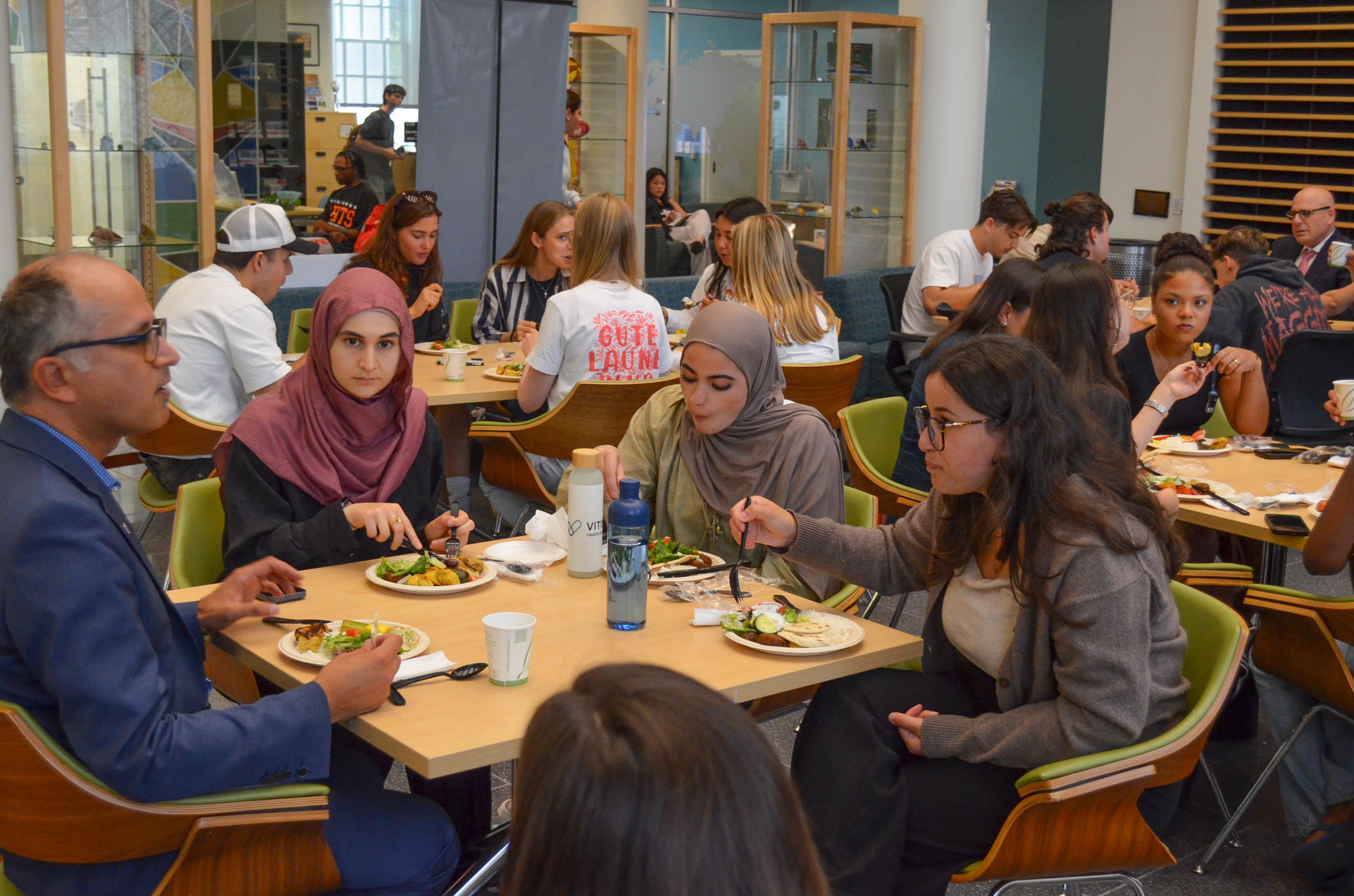 People gather around tables to eat in the HJ Patterson Global Crossroads atrium