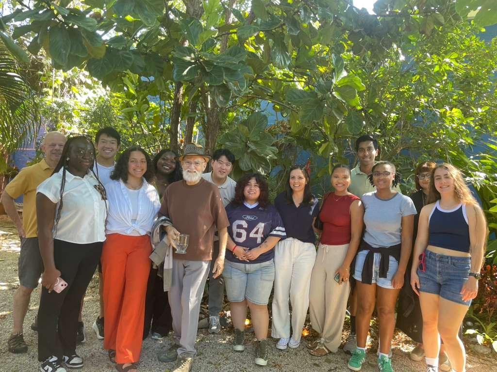 Students and instructors stand under greenery with Maestro Antonio Martorell outside his workshop